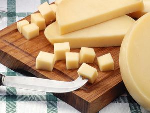 Provolone cheese on a wooden cutting board with a knife