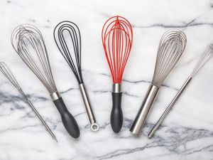 A variety of whisks on a marble surface