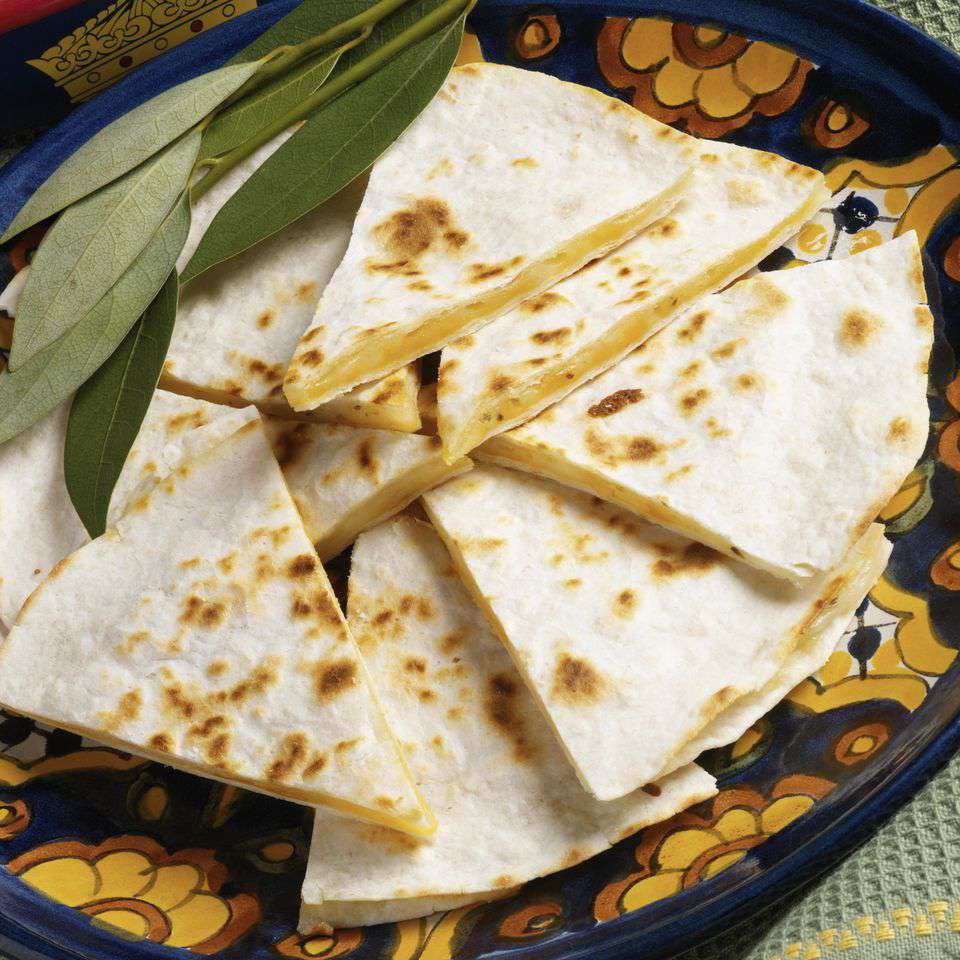 A platter full of cut pizza wrap sandwiches with some bay leaves off to the side