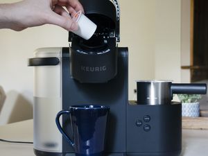 Hand placing K-Cup into Keurig K-Café displayed on countertop