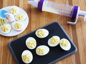 Wilton Dessert Decorator Plus Cake Decorating Tool displayed on butcher block countertop with nearby deviled eggs