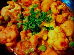 Indian curry in a black bowl, garnished with coriander