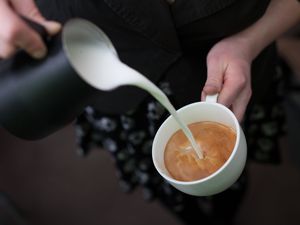 Barista pouring milk into espresso