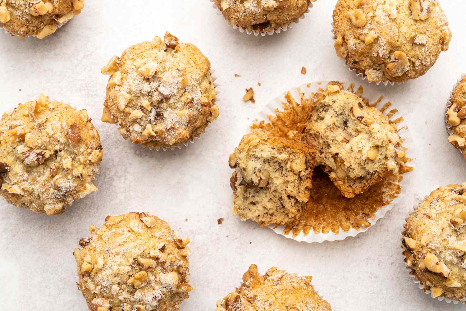 Overhead of ten vegan banana muffins with one in the center torn in half