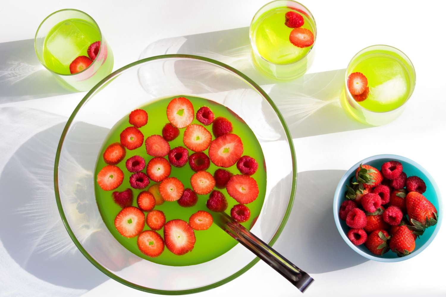 An overhead of Midori Berry Bliss Punch in bowl and three glasses