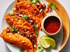 Birria Tacos served with a side of consome and lime wedges 