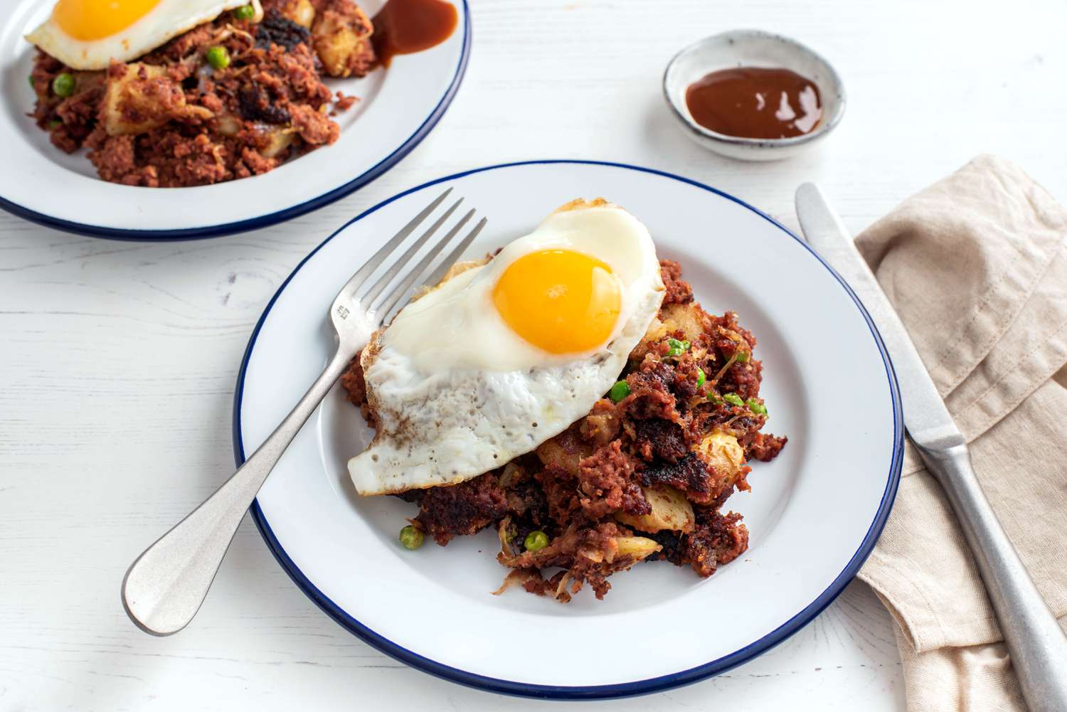 sunny side up egg on top of British Corned Beef Hash on a white plate