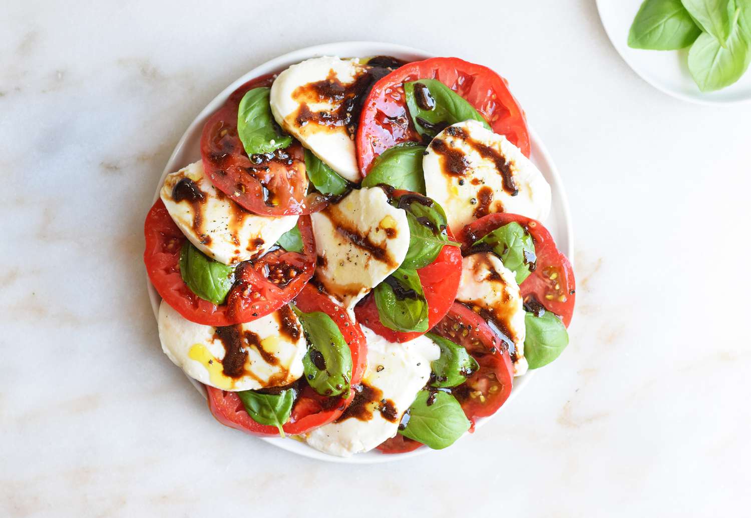 A beautifully layered caprese salad on a white plate