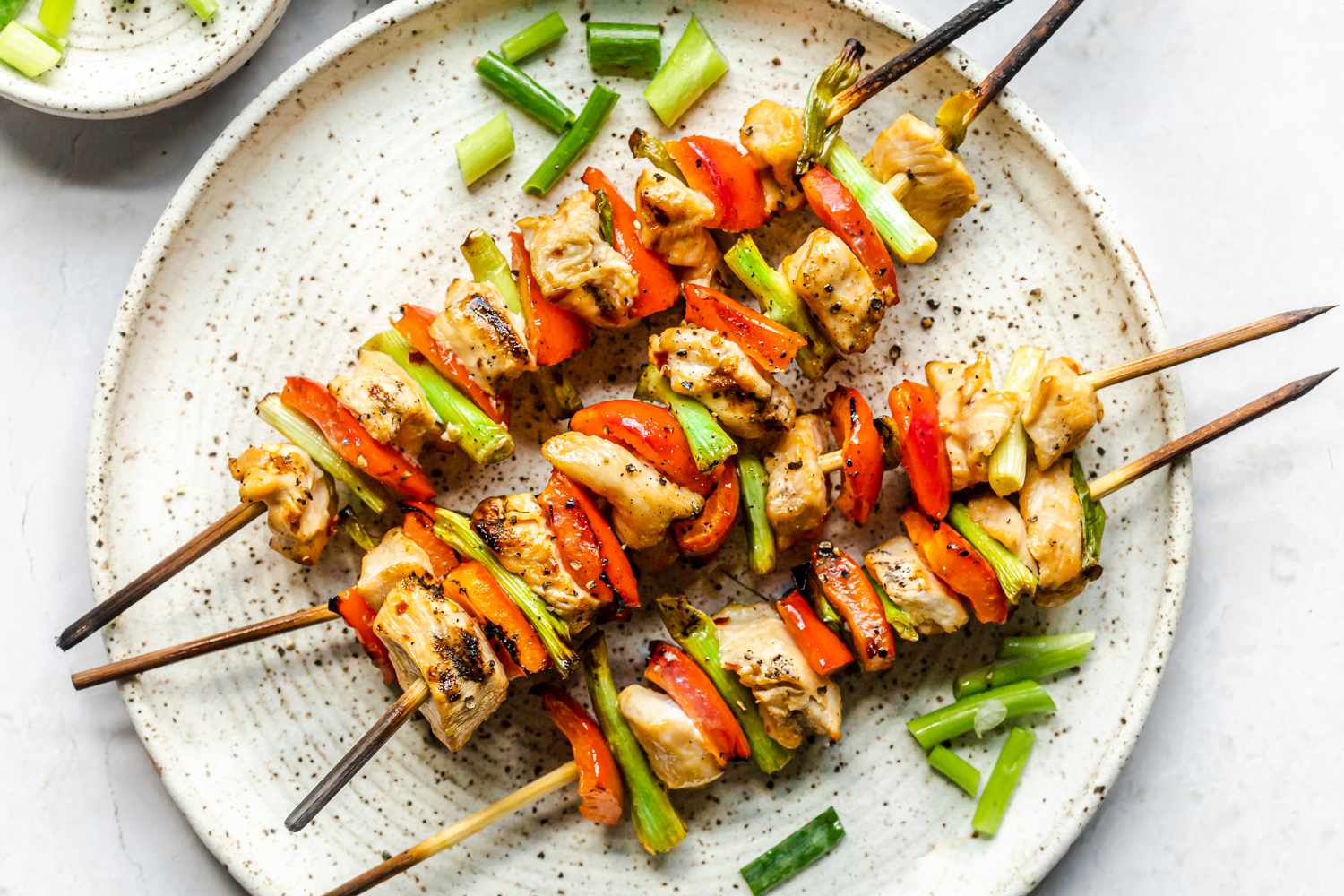 Four chicken kabob skewers on a white plate