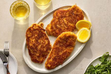 A platter with chicken Milanese, served with slices of lemon