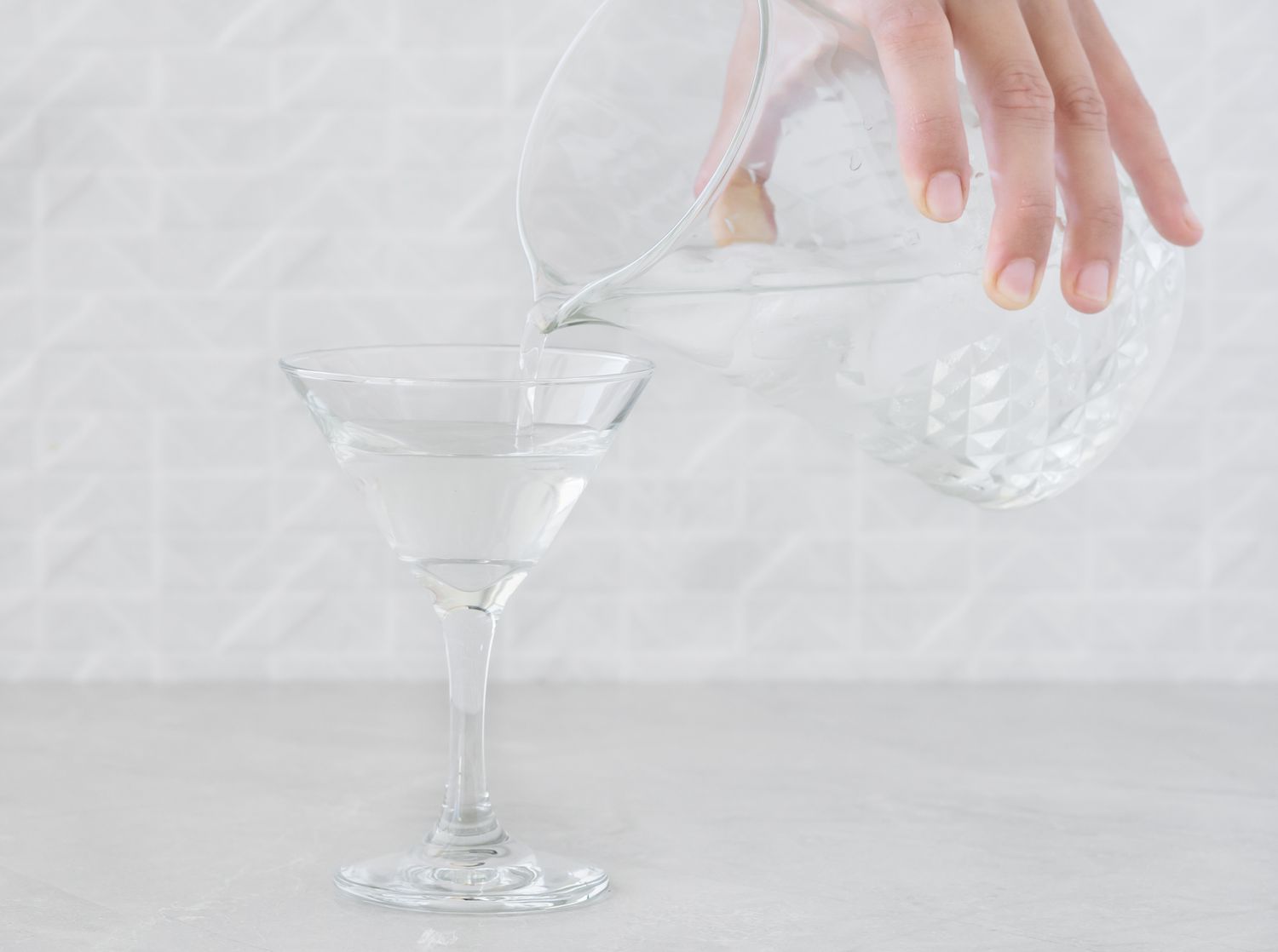 Straining the gin martini into a chilled cocktail glass