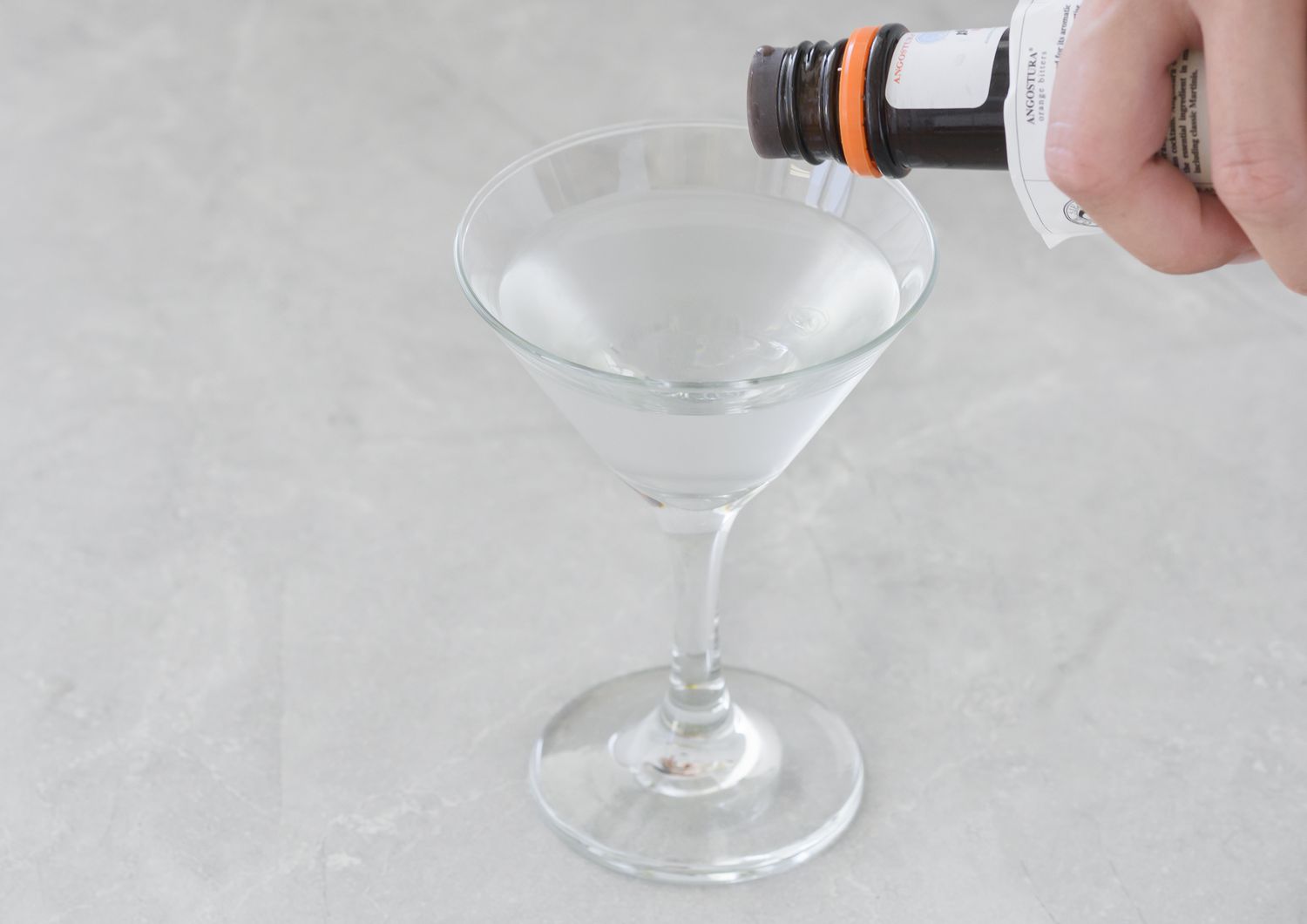 Orange bitters being added to gin martini