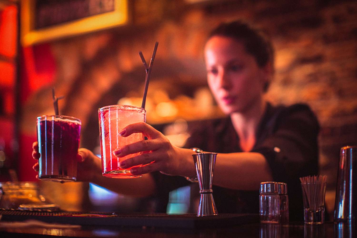 Close-up of young female bartender serving cocktails in cocktail bar