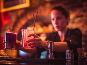 Close-up of young female bartender serving cocktails in cocktail bar