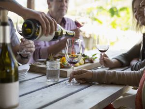 Couples wine tasting and enjoying charcuterie board on patio at winery tasting room