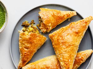 Indian Curry Puffs, with one cut open, on a grey plate