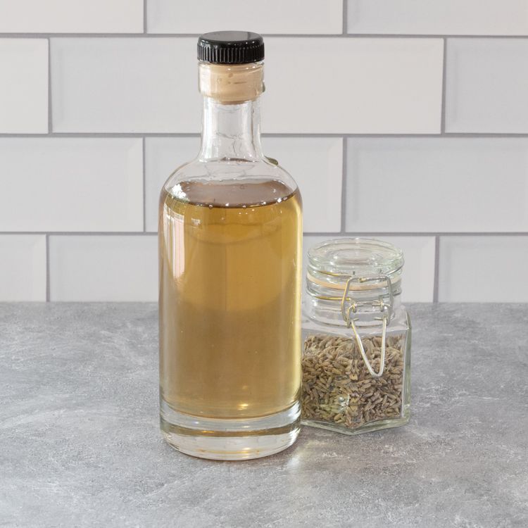 Lavender simple syrup in a glass bottle with a jar of dried lavender alongside