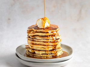 Stack of vanilla pancakes with butter and maple syrup on a plate