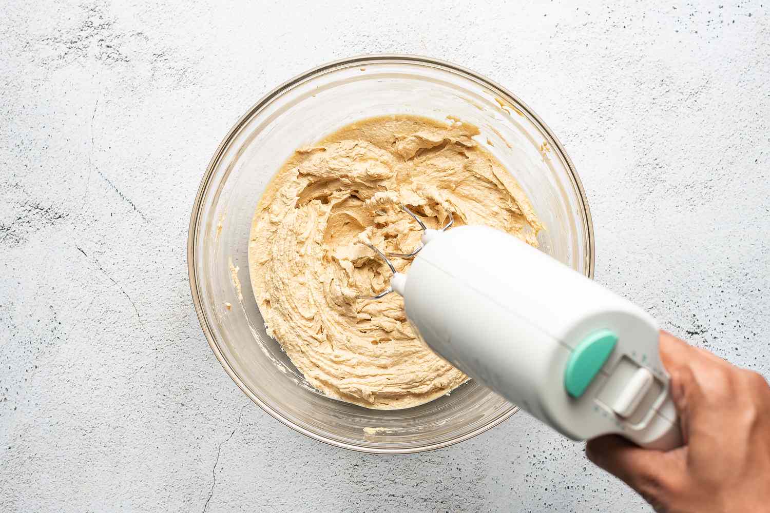 butter and sugar added to the mixture in the bowl, hand mixer 