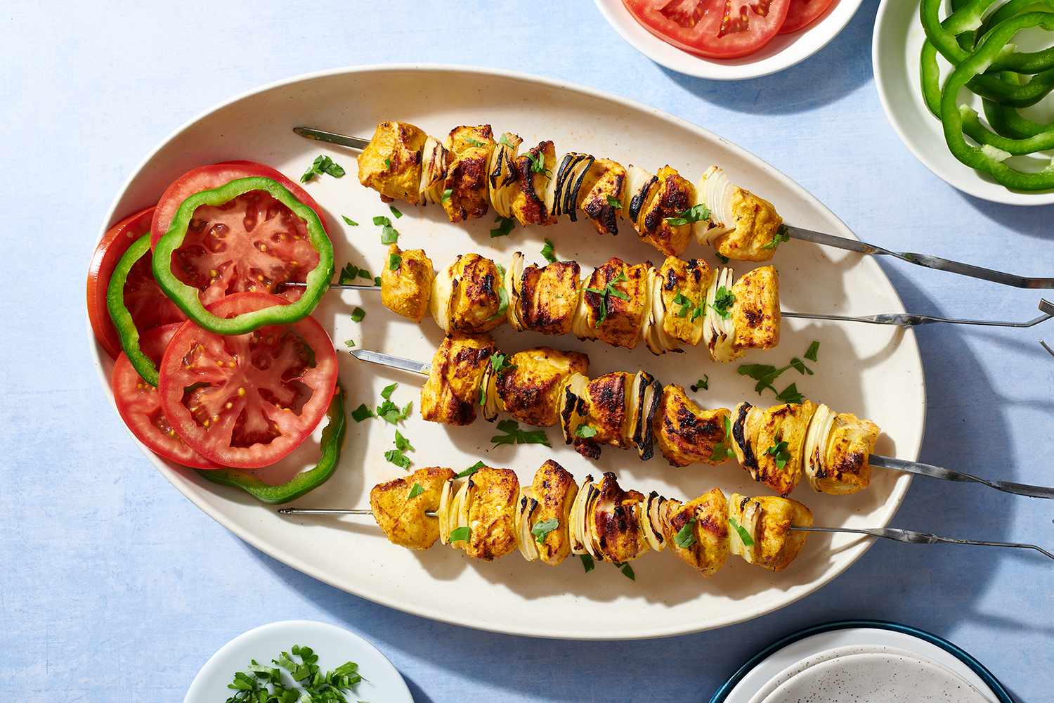 Egyptian-Style Chicken Kebabs on a platter with tomato slices and peppers 