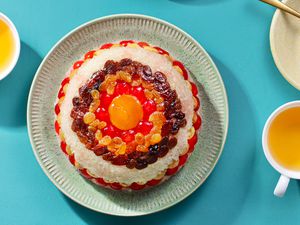 eight treasure rice pudding on a plate with cups of tea