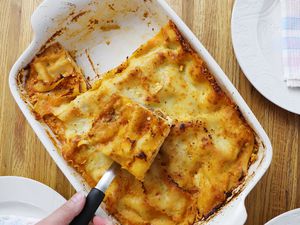 Hand using spatula to serve casserole from Emile Henry Modern Classics Rectangular Baker displayed on butcher block counter