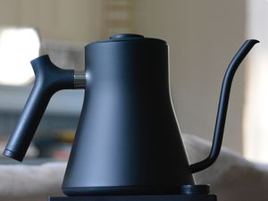 Fellow Stagg EKG Electric Kettle displayed on a dark surface against a blurred background