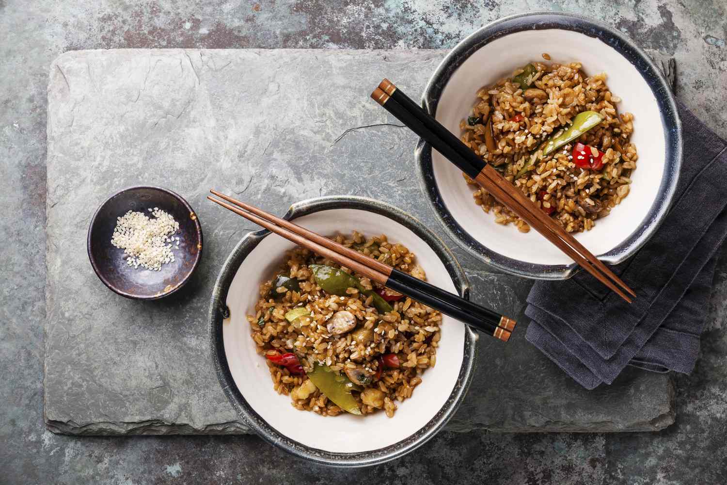 Fried rice with vegetables and sesame on stone slate background