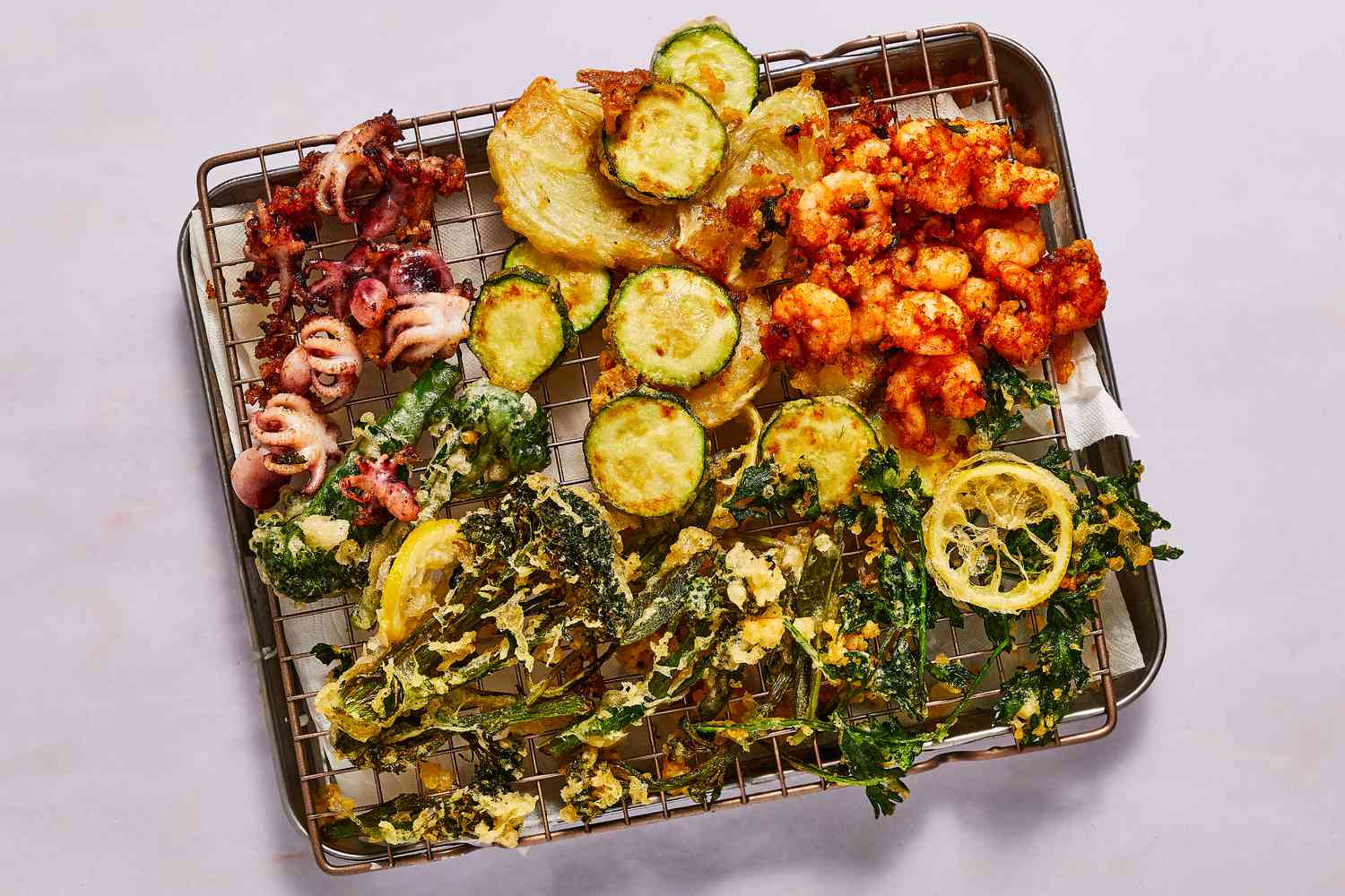 fried frito misto pieces draining on a rack set over a baking sheet lined with paper towel