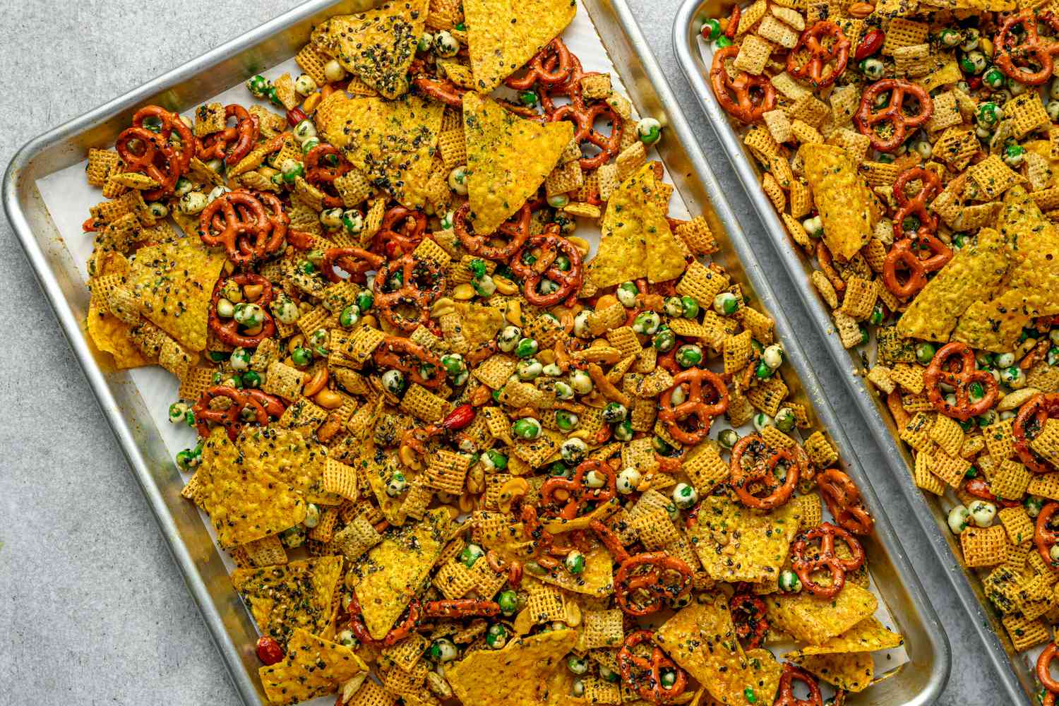 furikake seasoning sprinkled on top of chex mix on two sheet pans