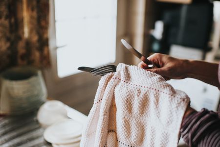 person drying forks and knives with a kitchen towel