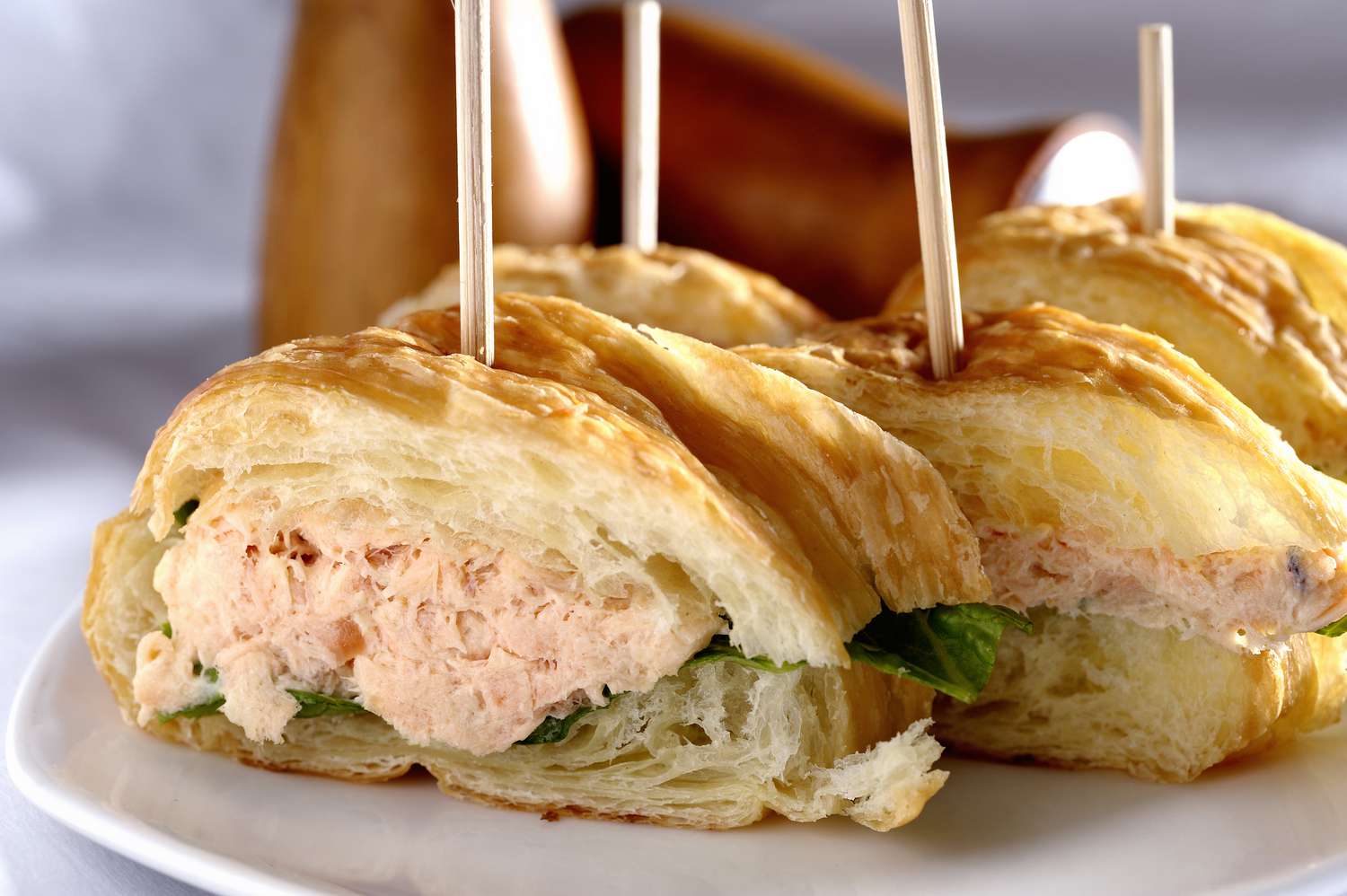 Four salmon salad croissant sandwiches on a plate