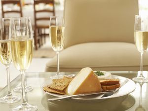 Glasses of wine by plate of cheese and biscuits on coffee table