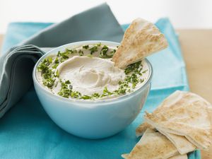 Bowl of hummus and tahini dip with pita bread on table