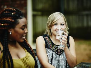 Smiling woman sharing wine with friends