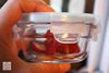 Person holding closed round container with strawberries from the Glasslock 18-Piece Assorted Oven-Safe Container Set filled with strawberries