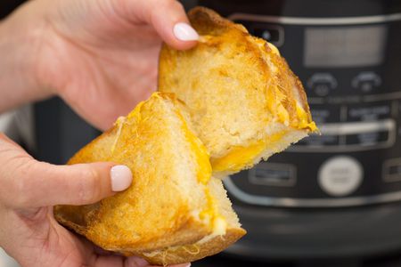 Hand holding a grilled cheese sandwich that has been cut in half