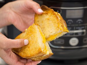 Hand holding a grilled cheese sandwich that has been cut in half