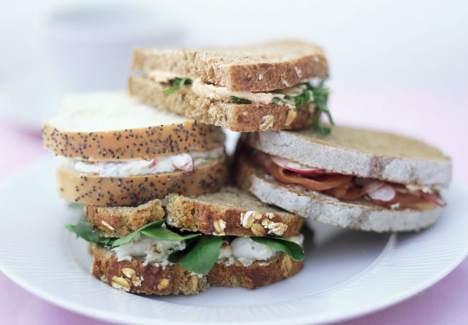 Four ham salad sandwiches stacked on each other on a plate