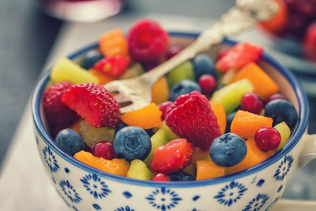 A white and blue bowl filled with a honeyed fruit salad