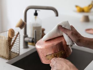 Copper pot dried with microfiber cloth in front of sink