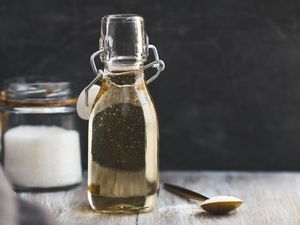 Simple syrup in a bottle and sugar in a jar and on a spoon