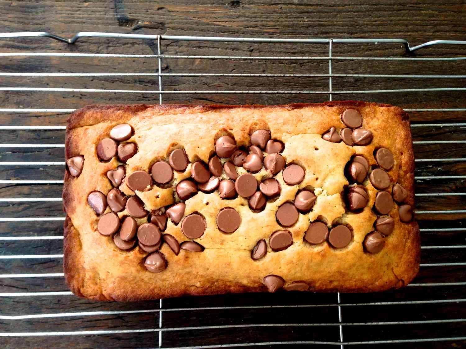 A baked chocolate chip banana bread resting on a cooling rack