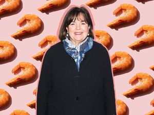 A photo of Ina Garten in front of a light pink background with shrimp evenly spaced on it