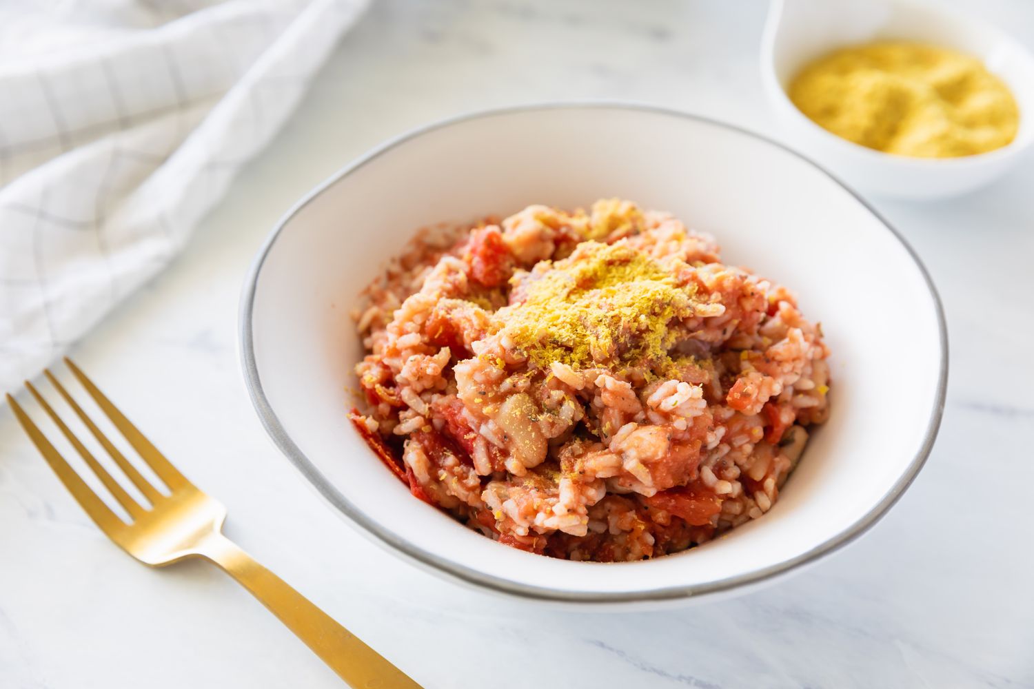 A bowl of gluten-free and vegan Italian rice and beans with a gold fork off to the side