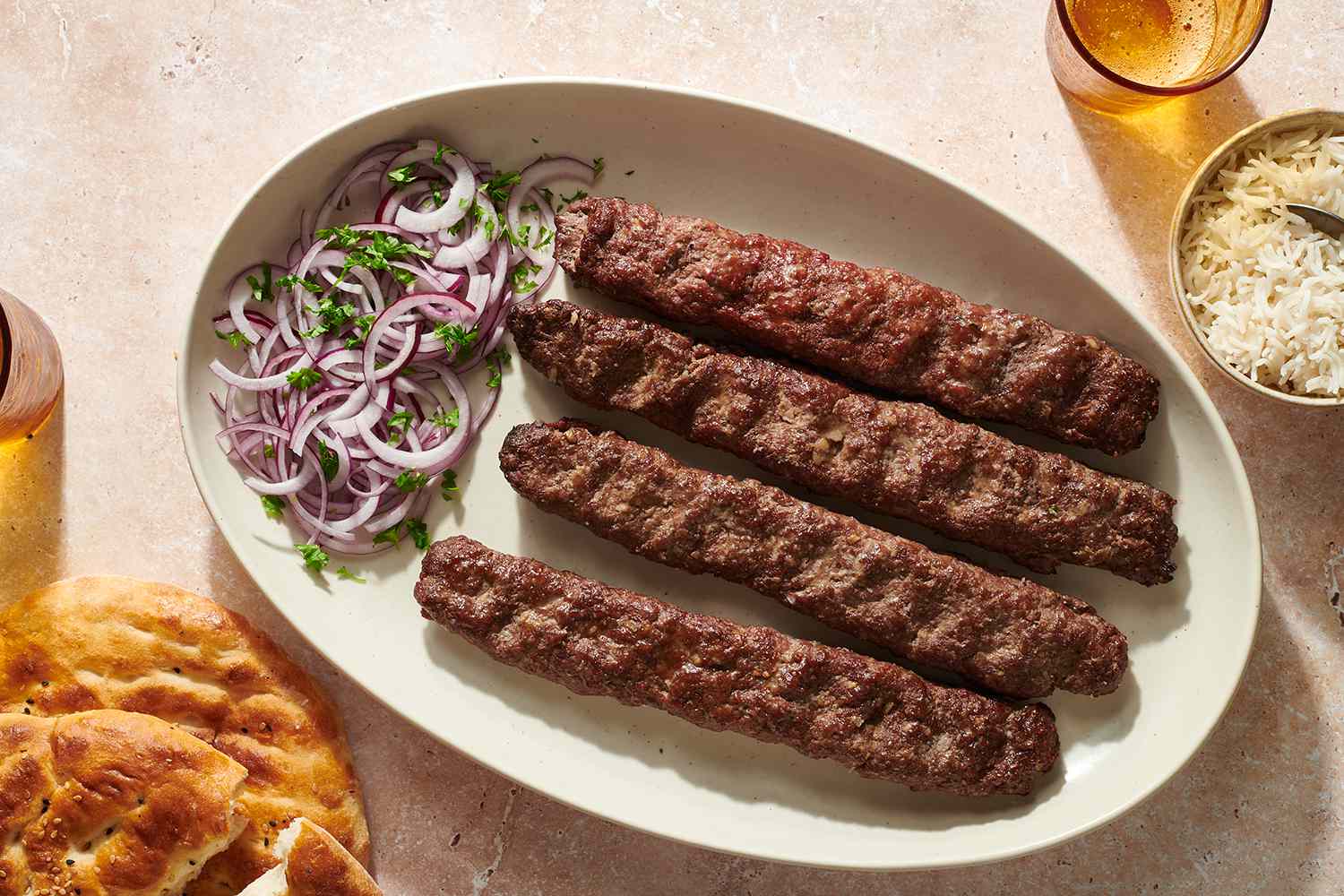 Kabob Koobideh (Persian Grilled Kebabs) on a platter with an onion salad 