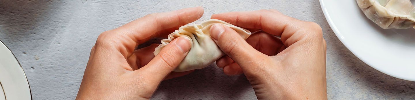 Hands folding a potsticker