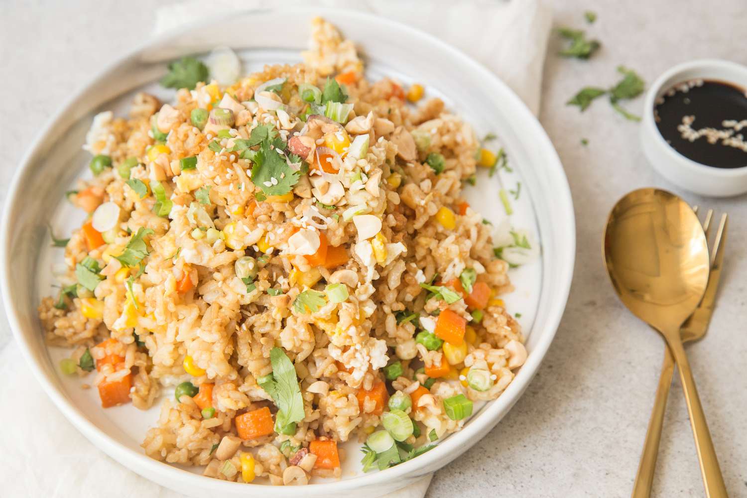 A plate of a Leftovers night fried rice dish with gold cutlery off to the side 