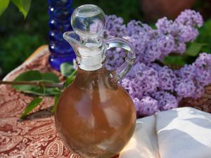 Lilac simple syrup in a glass jar with lilacs on a table