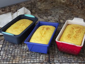 Several loaves of bread in loaf pans cooling on a wire rack